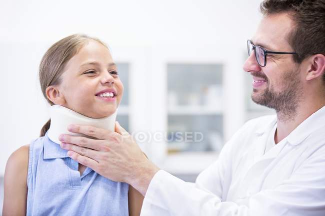 Homme médecin appliquant le soutien du cou à la jeune fille . — Photo de stock