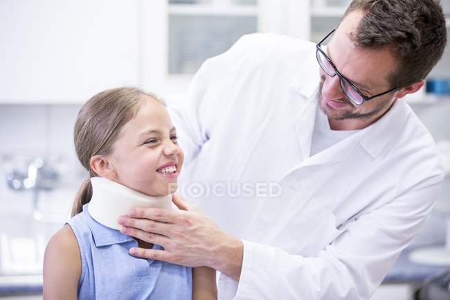 Medico maschio che applica il supporto del collo alla giovane ragazza . — Foto stock