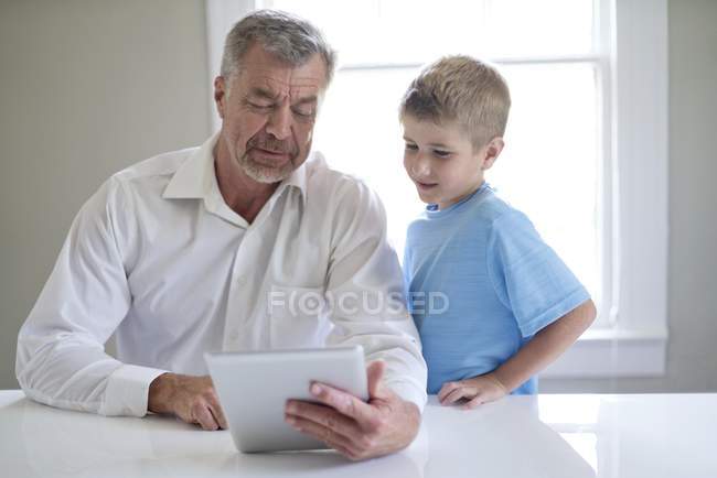 Дід і онук використовують цифровий планшет у приміщенні . — стокове фото
