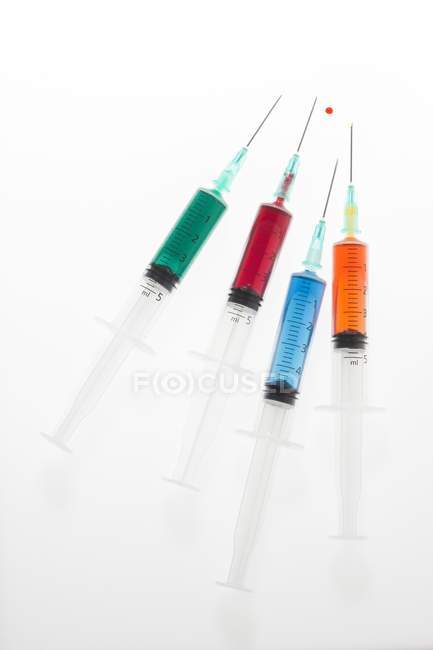 Quatre seringues avec des liquides colorés, plan studio . — Photo de stock