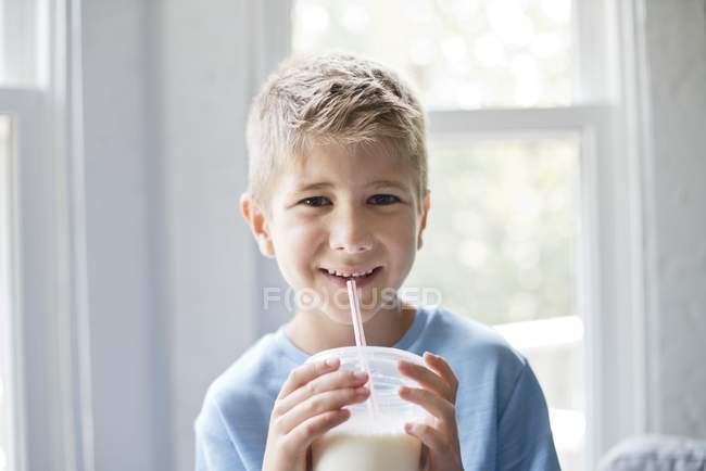 Preteen menino bebendo milkshake com palha bebendo — Fotografia de Stock