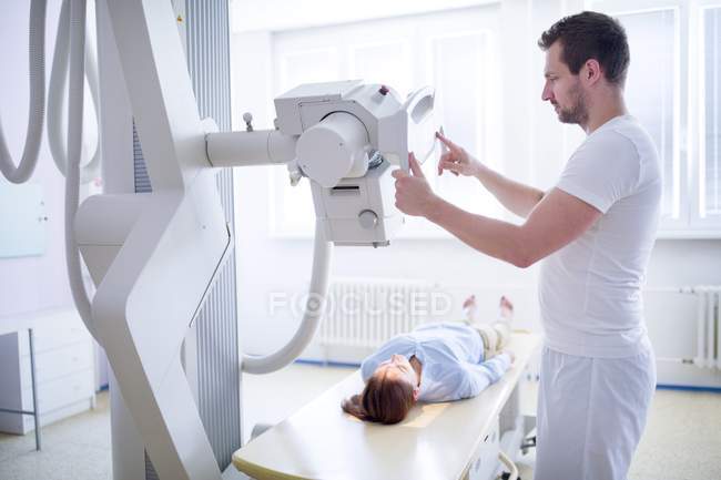 Doctor using x-ray machine with female patient lying down. — Stock Photo