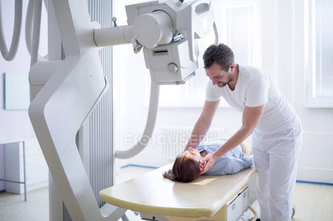 Doctor ajustando el cuello del paciente femenino antes de la radiografía . - foto de stock