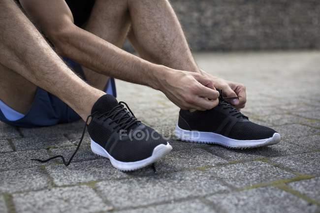 Uomo allacciatura lacci delle scarpe su formatori . — Foto stock