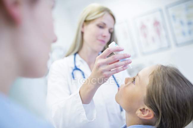 Female doctor putting eye drops into young girl eyes. — Stock Photo