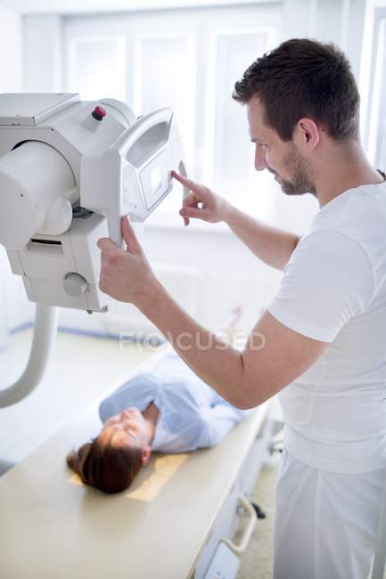 Médico usando máquina de raios X com paciente do sexo feminino deitado . — Fotografia de Stock