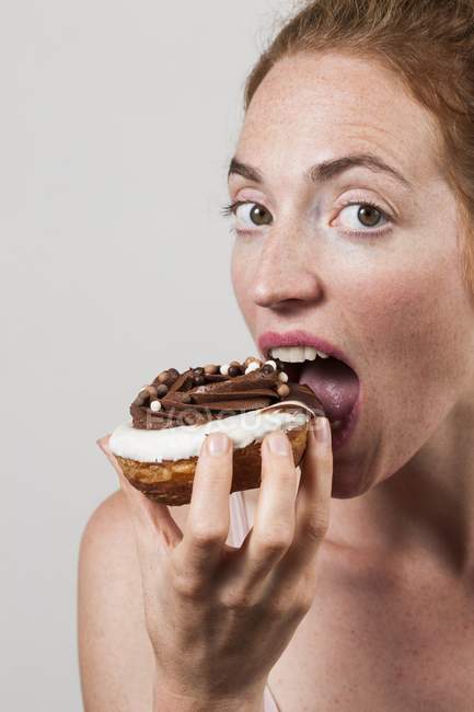 Portrait of woman eating chocolate doughnut. — Stock Photo