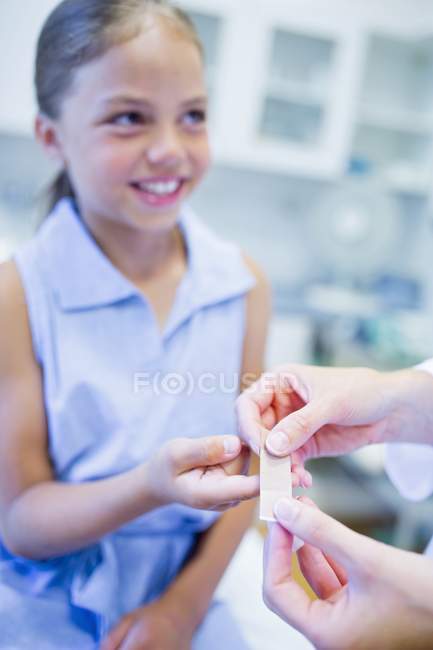 Nurse applying plaster to girl hand. — Stock Photo