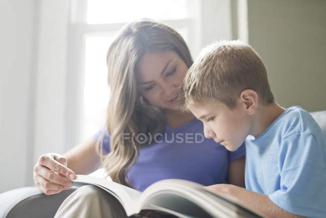 Mother and son reading book together. — Stock Photo