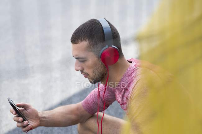 Чоловік в навушниках слухає музику на смартфоні . — стокове фото