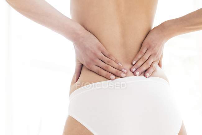 Mulher esfregando parte inferior das costas, visão traseira . — Fotografia de Stock