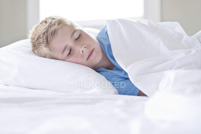 Menino dormindo na cama dentro de casa . — Fotografia de Stock