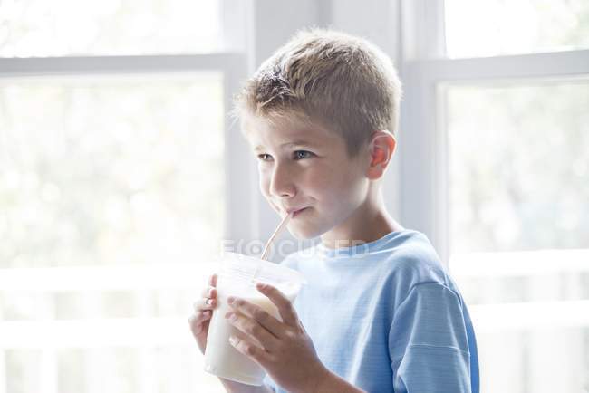 Junge trinkt Milchshake mit Trinkhalm — Stockfoto