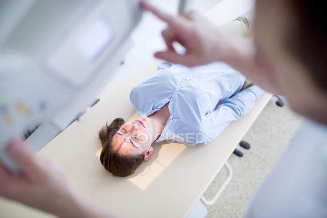 Máquina de rayos X con paciente hembra acostada . - foto de stock