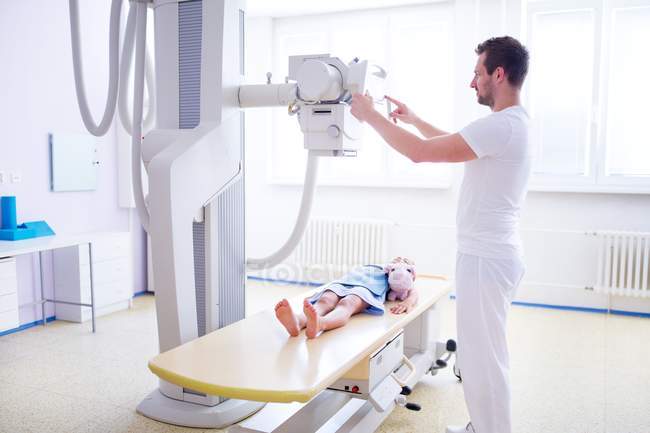 Médico preparando máquina de rayos X con paciente infantil en el hospital . - foto de stock