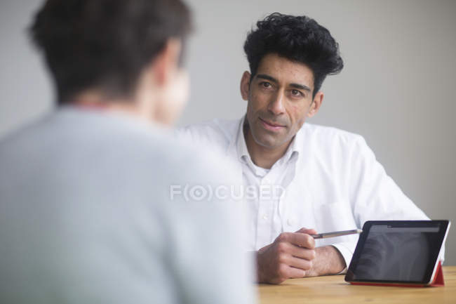 Doctor discussing X-ray on digital tablet with patient. — Stock Photo