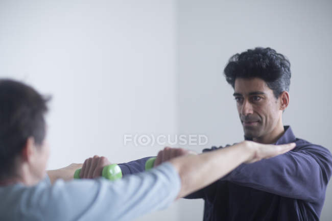 Fisioterapista esaminando mani di donna matura . — Foto stock
