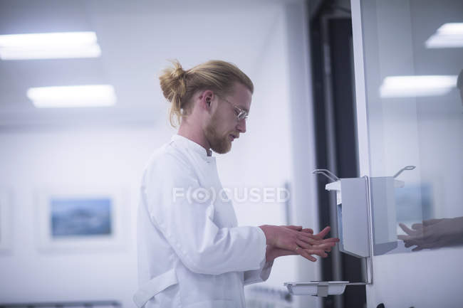 Médico masculino usando higienizador de mãos na clínica . — Fotografia de Stock
