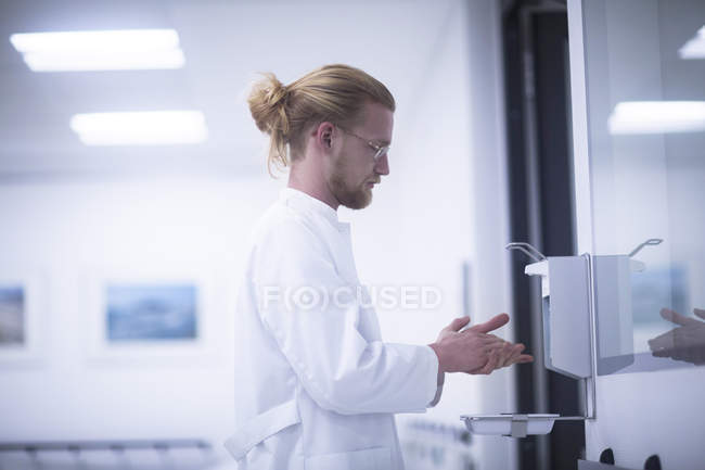 Médico masculino usando desinfectante de manos en la clínica . - foto de stock