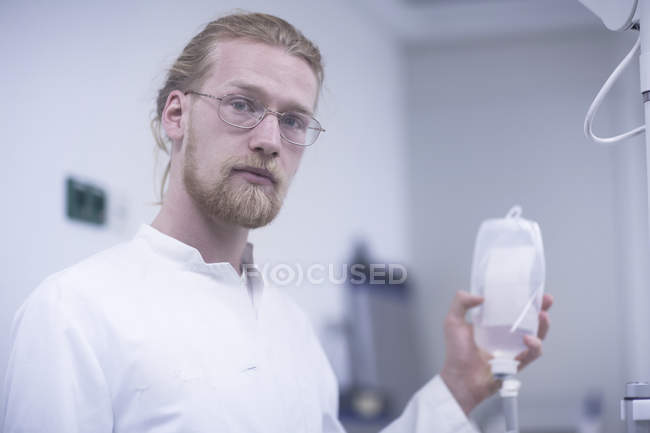 Радиолог держит бутылку раствора и смотрит в камеру . — стоковое фото