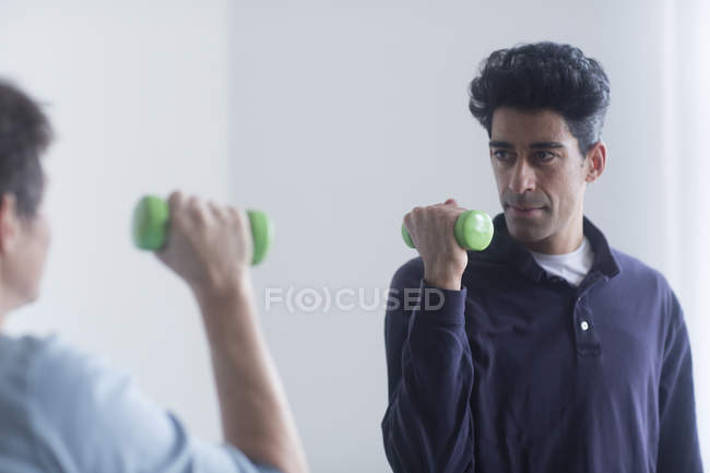 Male physiotherapist and mature female patient working with dumbbells. — Stock Photo