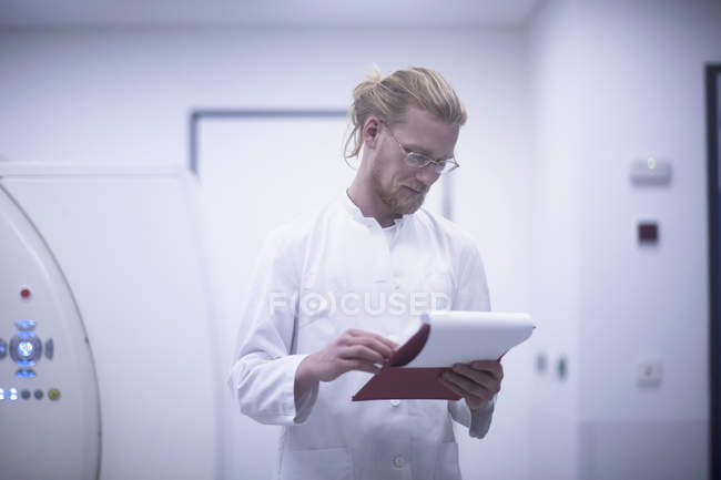 Radiologo guardando gli appunti con sala scanner ct . — Foto stock