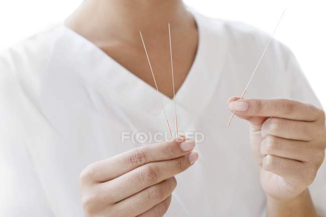 Vista cortada de acupunturista fêmea segurando agulhas de acupuntura . — Fotografia de Stock