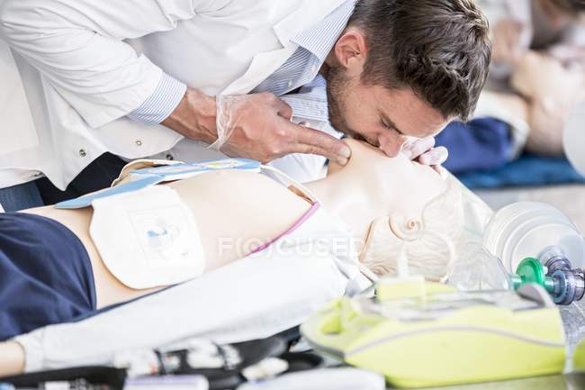 Male doctor practicing rescue breathing on cardiopulmonary resuscitation training dummy. — Stock Photo