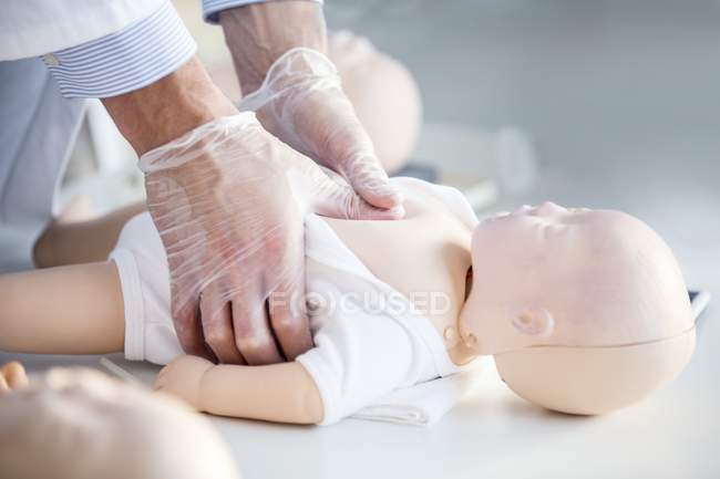 Médecin pratiquant la compression thoracique sur mannequin d'entraînement pour bébé . — Photo de stock