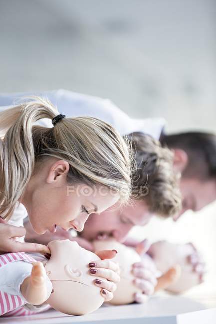 Médicos femeninos y masculinos practicando reanimación cardiopulmonar en maniquíes de entrenamiento infantil . - foto de stock