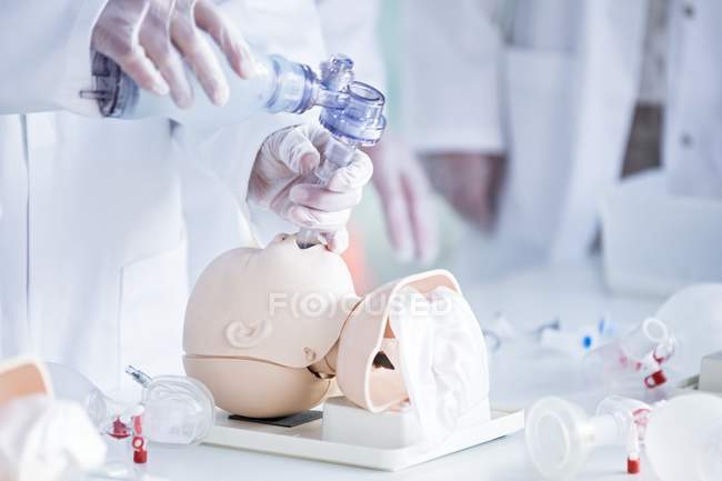 Doctor practicing tracheal intubation on infant training dummy. — Stock Photo