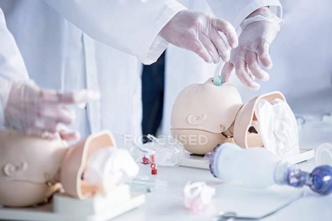 Doctors practicing tracheal intubation on infant training dummies. — Stock Photo