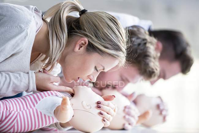 Médicos femeninos y masculinos practicando reanimación cardiopulmonar en maniquíes de entrenamiento infantil . - foto de stock