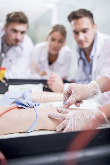 Medical students practicing inserting intravenous line on training dummy. — Stock Photo