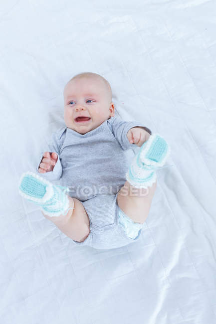 Overhead view of baby boy lying on back in bed. — Stock Photo