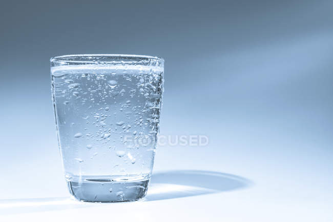 Glass of water with condensation on plain background. — Stock Photo