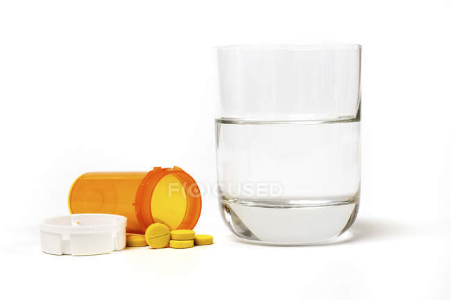 Medicação e vidro de água sobre fundo branco . — Fotografia de Stock
