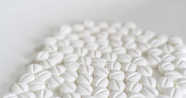 Pilules blanches sur fond blanc, gros plan . — Photo de stock