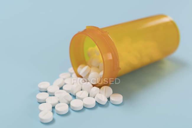 Weiße Pillen aus geöffnetem Plastikbehälter verschüttet. — Stockfoto