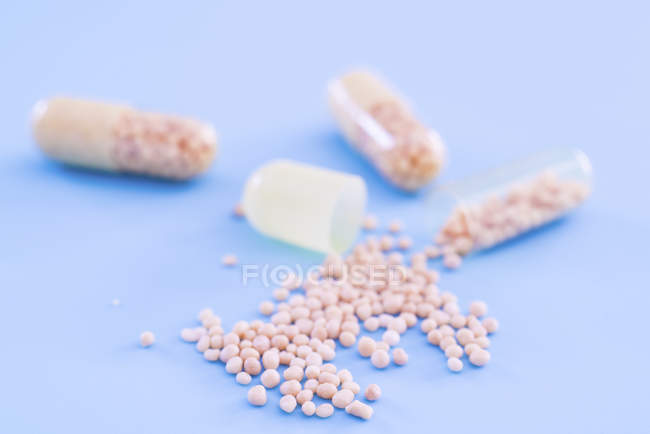 Pills pouring from dietary supplement capsules. — Stock Photo