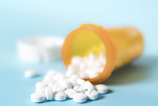 Weiße Pillen aus geöffnetem Plastikbehälter verschüttet. — Stockfoto