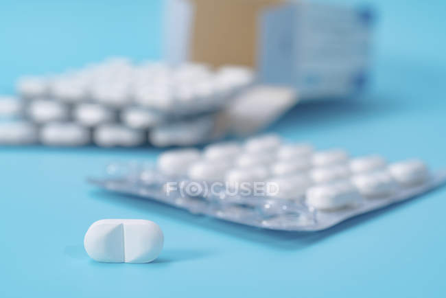 Film-coated tablets in blisters on blue background. — Stock Photo