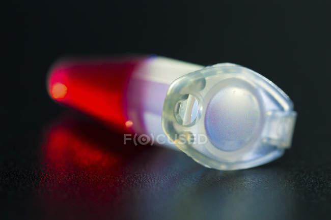 Nahaufnahme der Probe auf roter Flüssigkeit in Zentrifugenröhre. — Stockfoto