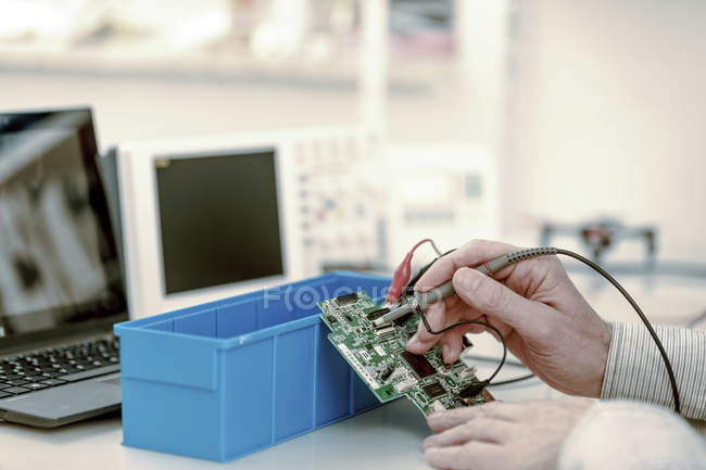 Gros plan d'un technicien réparant une carte de circuit imprimé dans un laboratoire d'électronique . — Photo de stock