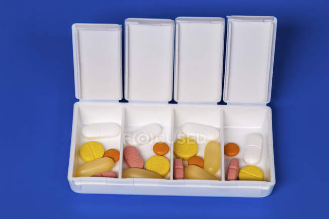 White organizer with various tablets on blue background. — Stock Photo