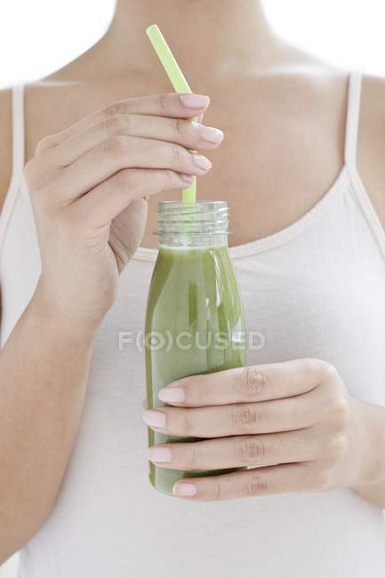 Vista ritagliata della donna che beve frullato verde dalla bottiglia . — Foto stock