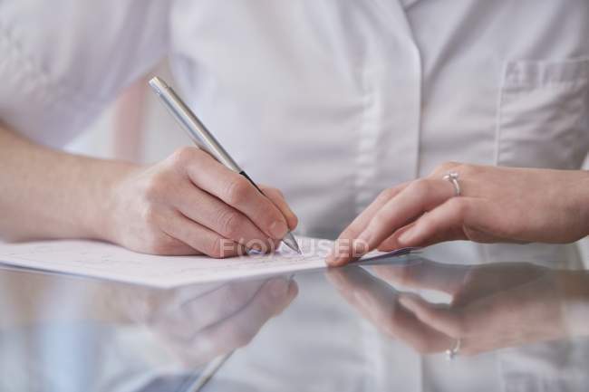Cropped view of female osteopath making notes. — Stock Photo