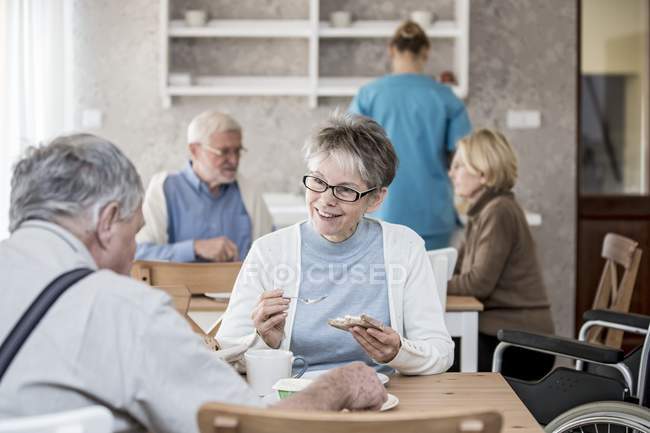 Senior adults eating breakfast in care home. — Stock Photo