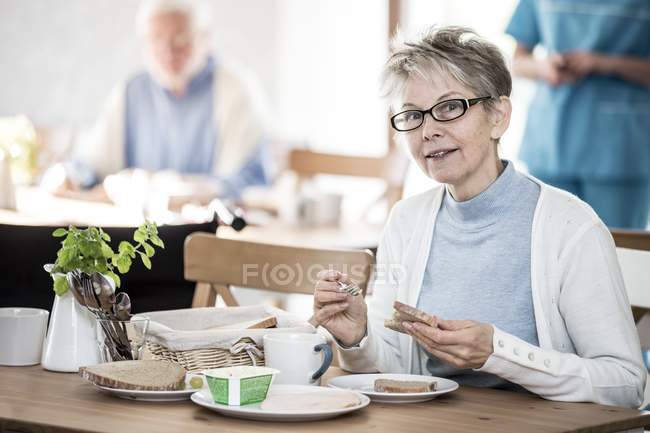 Mujer mayor comiendo comida en el hogar de cuidado . - foto de stock
