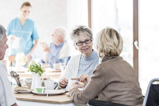 Seniorinnen reden beim Frühstück im Pflegeheim. — Stockfoto